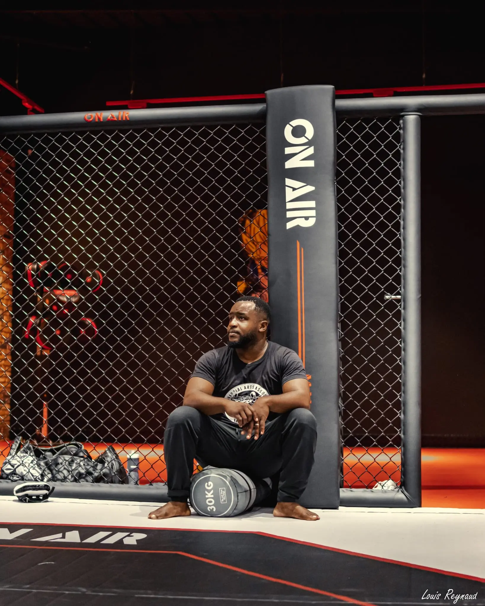 Le coach de Team WILL assis au pied de la cage de MMA